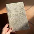 Floral-patterned notebook held by a hand on a wooden surface