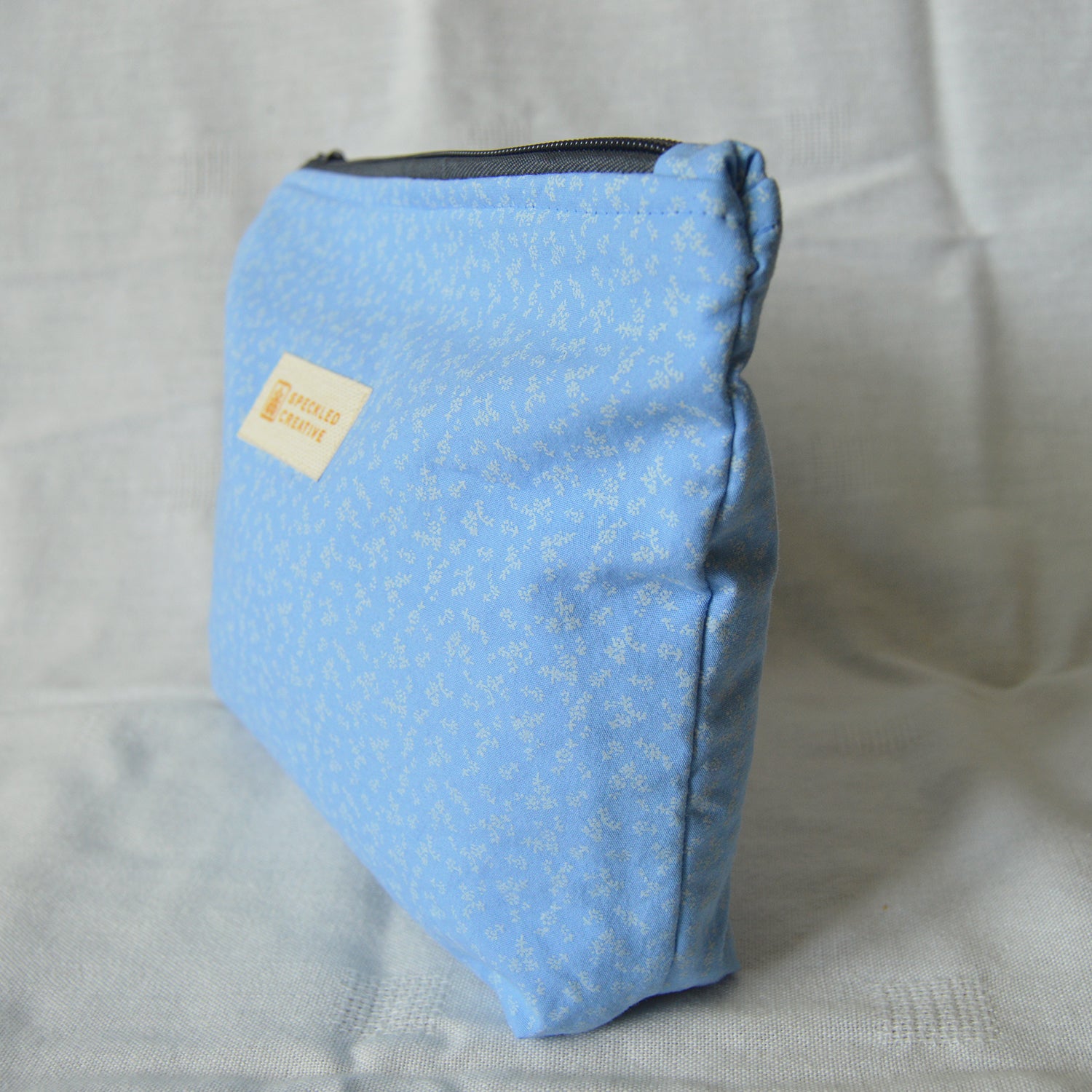 Blue pouch with a floral pattern on a light gray background