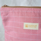 Close up of a pink checkered pouch with a Speckled Creative label on a light gray background