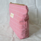 Pink checkered pouch with a brown zipper on a white background
