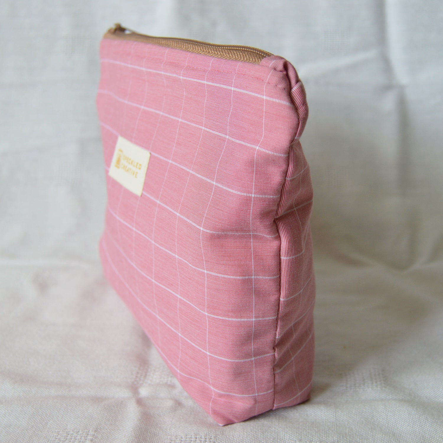 Pink checkered pouch with a brown zipper on a white background