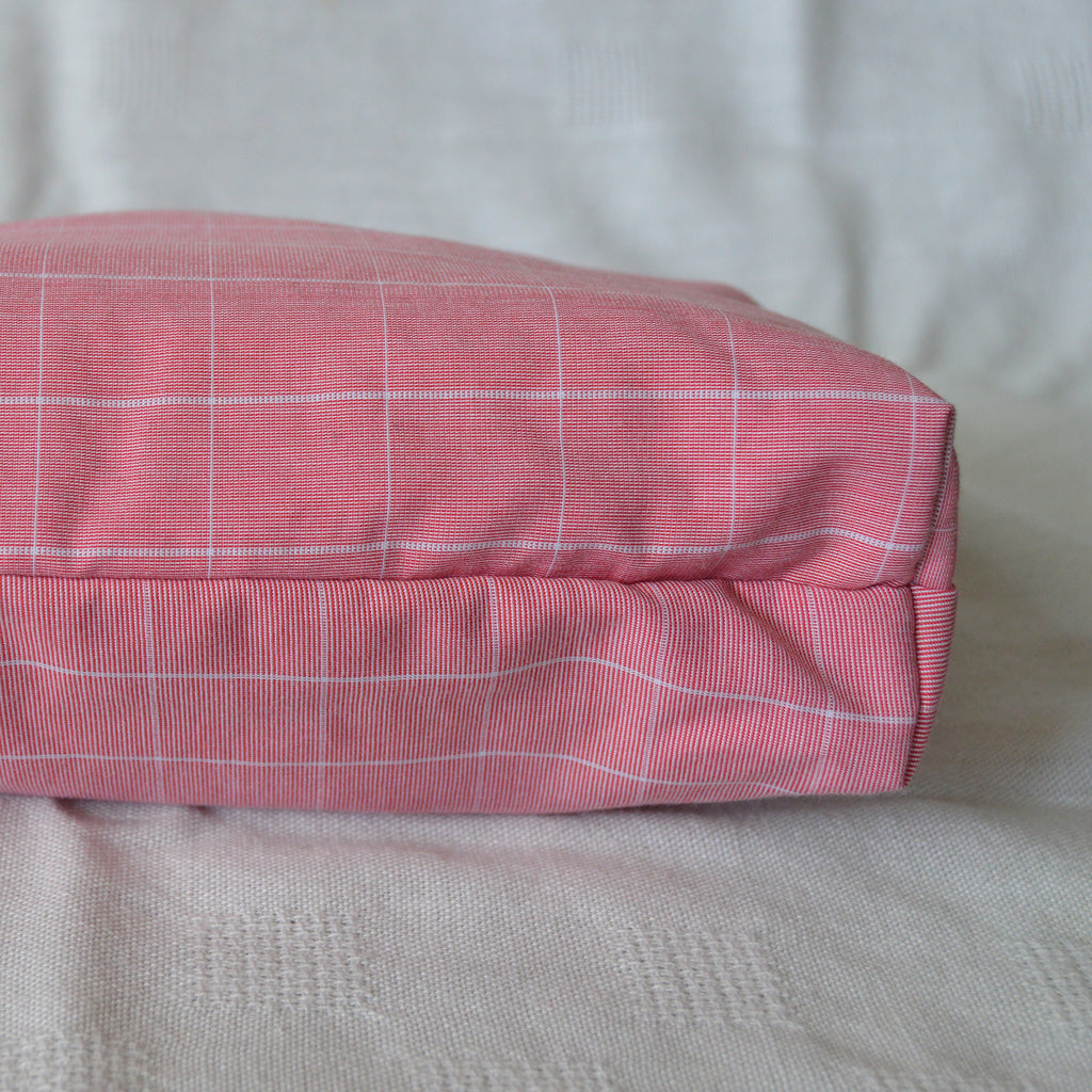 Bottom of a pink checkered pouch on a beige surface