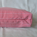 Bottom of a pink checkered pouch on a beige surface