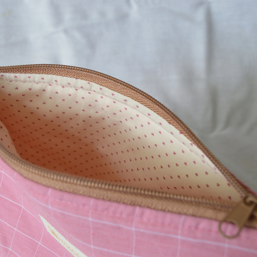 Close-up of a zipper pouch with a pink grid background