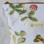 Fabric pouch with floral design and Speckled Creative label on a white background