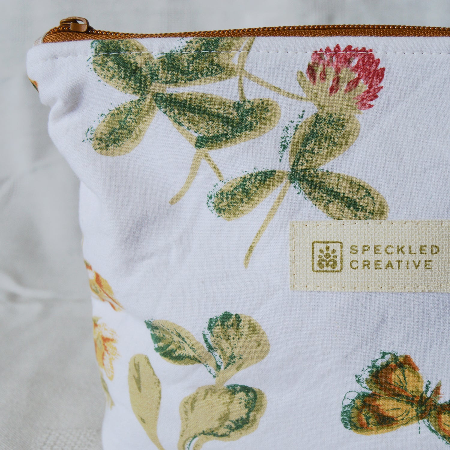 Fabric pouch with floral design and Speckled Creative label on a white background