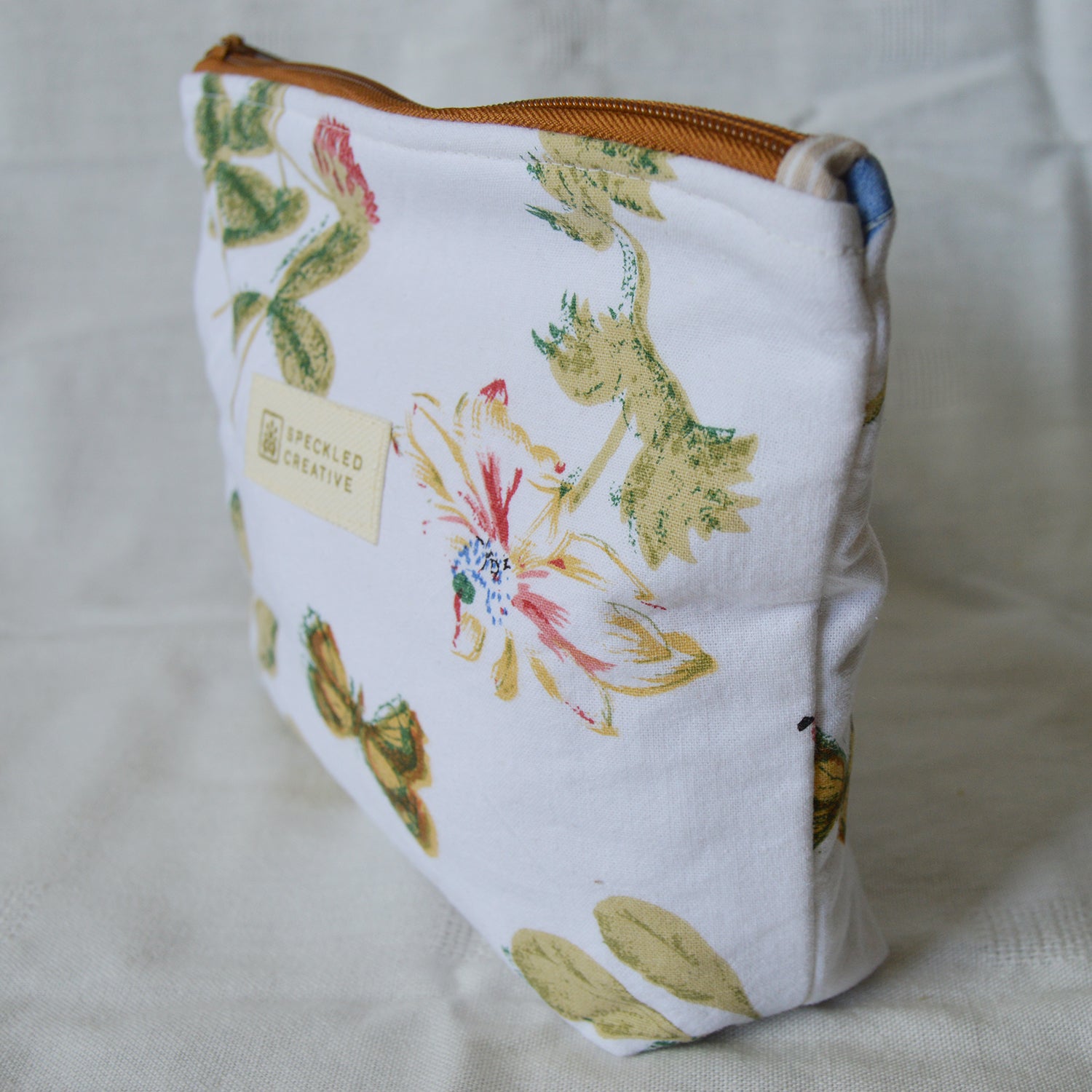 Fabric pouch with floral and nature-themed design on a light background