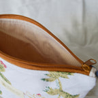 Close-up of a pouch with a floral pattern and brown zipper on a light background