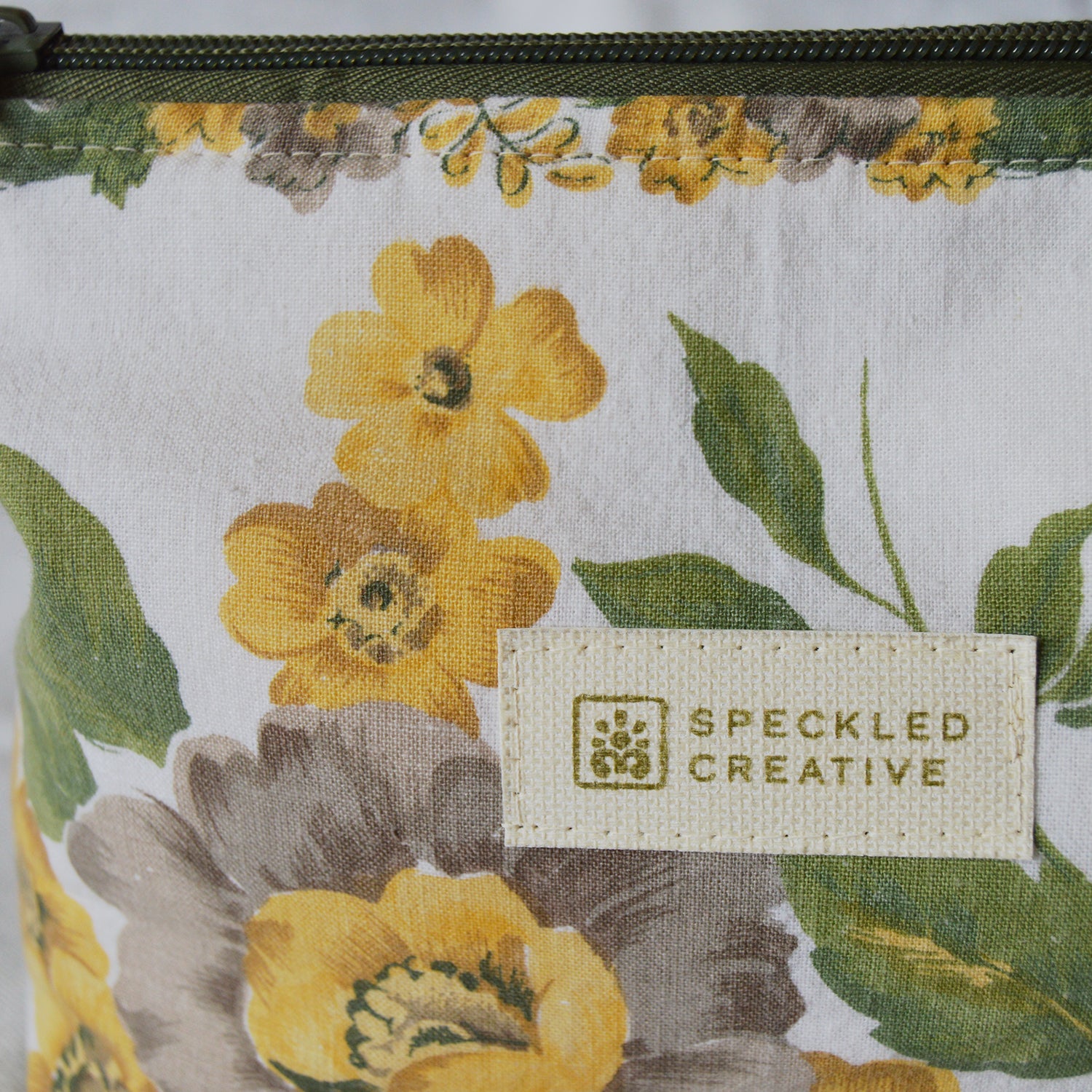 Close up of floral-patterned pouch with 'Speckled Creative' label