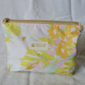 Floral-patterned pouch with gold zipper on a light gray background