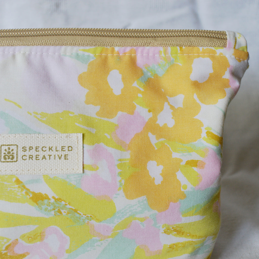 Close up of floral-patterned pouch with 'Speckled Creative' label on a white background
