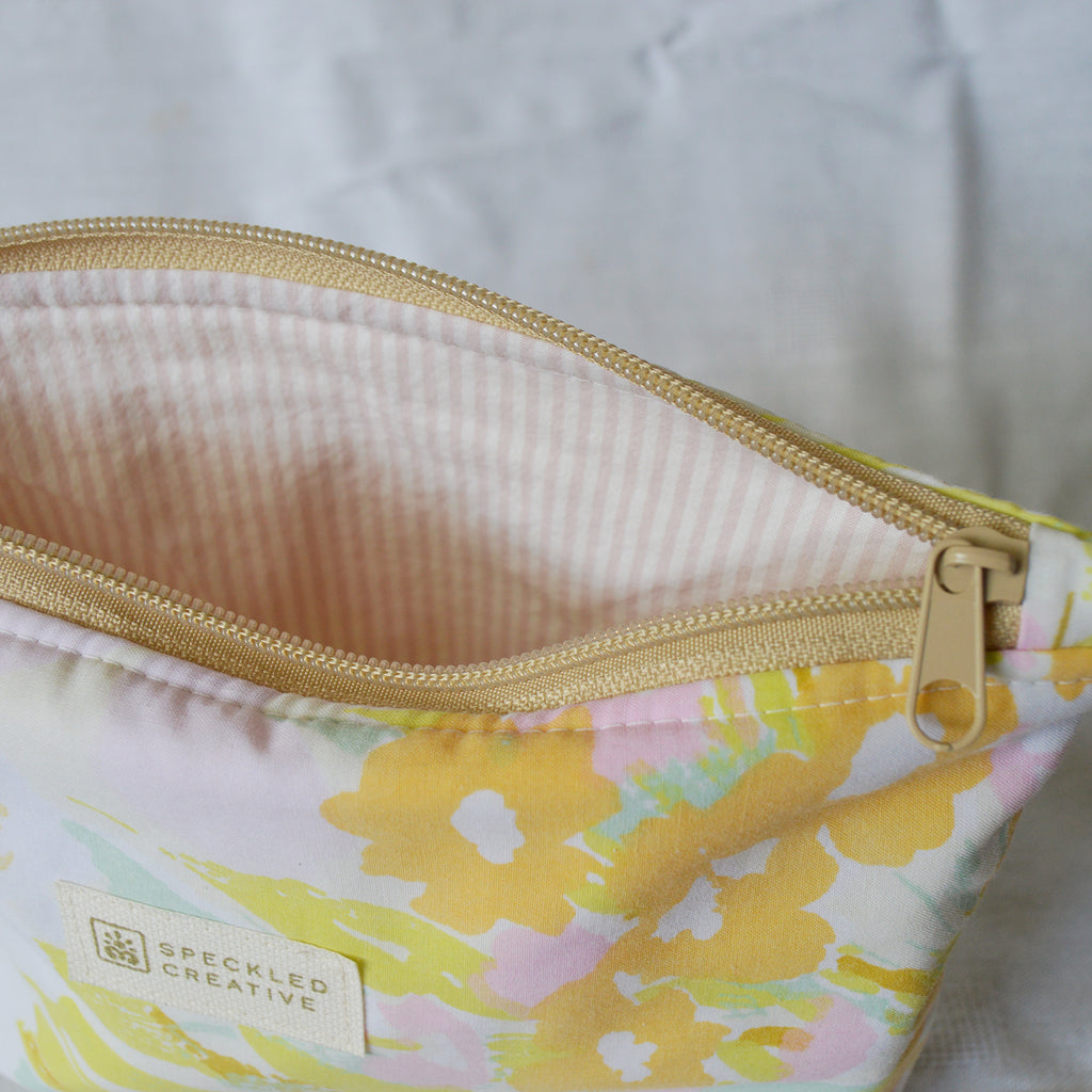 Floral pouch with gold zipper on a light background