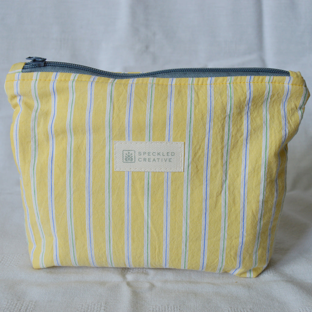 Yellow striped pouch with a Speckled Creative label on a light gray background