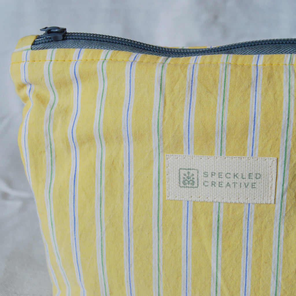 Yellow striped pouch with a visible brand label on a light gray background