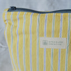 Yellow striped pouch with a visible brand label on a light gray background