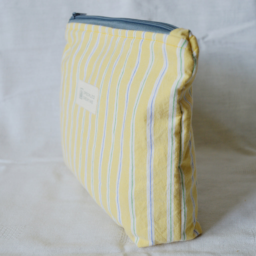 Yellow striped pouch with a blue zipper on a white background