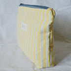 Yellow striped pouch with a blue zipper on a white background
