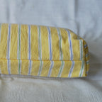 Bottom of a pouch with yellow with blue and green stripes on a textured surface