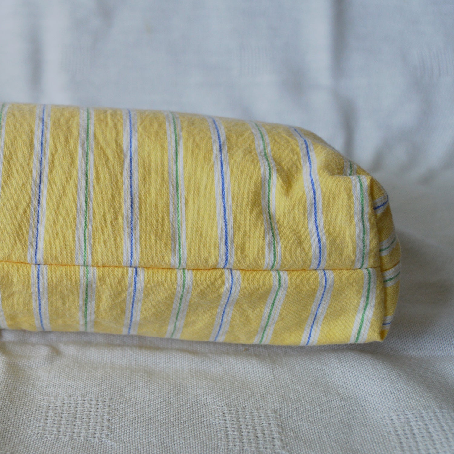 Bottom of a pouch with yellow with blue and green stripes on a textured surface