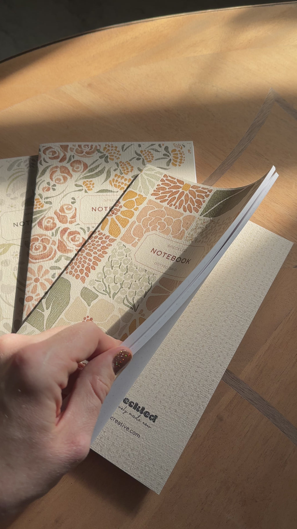 Flipping through pages of a dotted-grid notebook on a wooden surface
